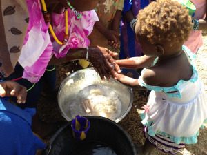 A little girl learns to wash her hands before eating